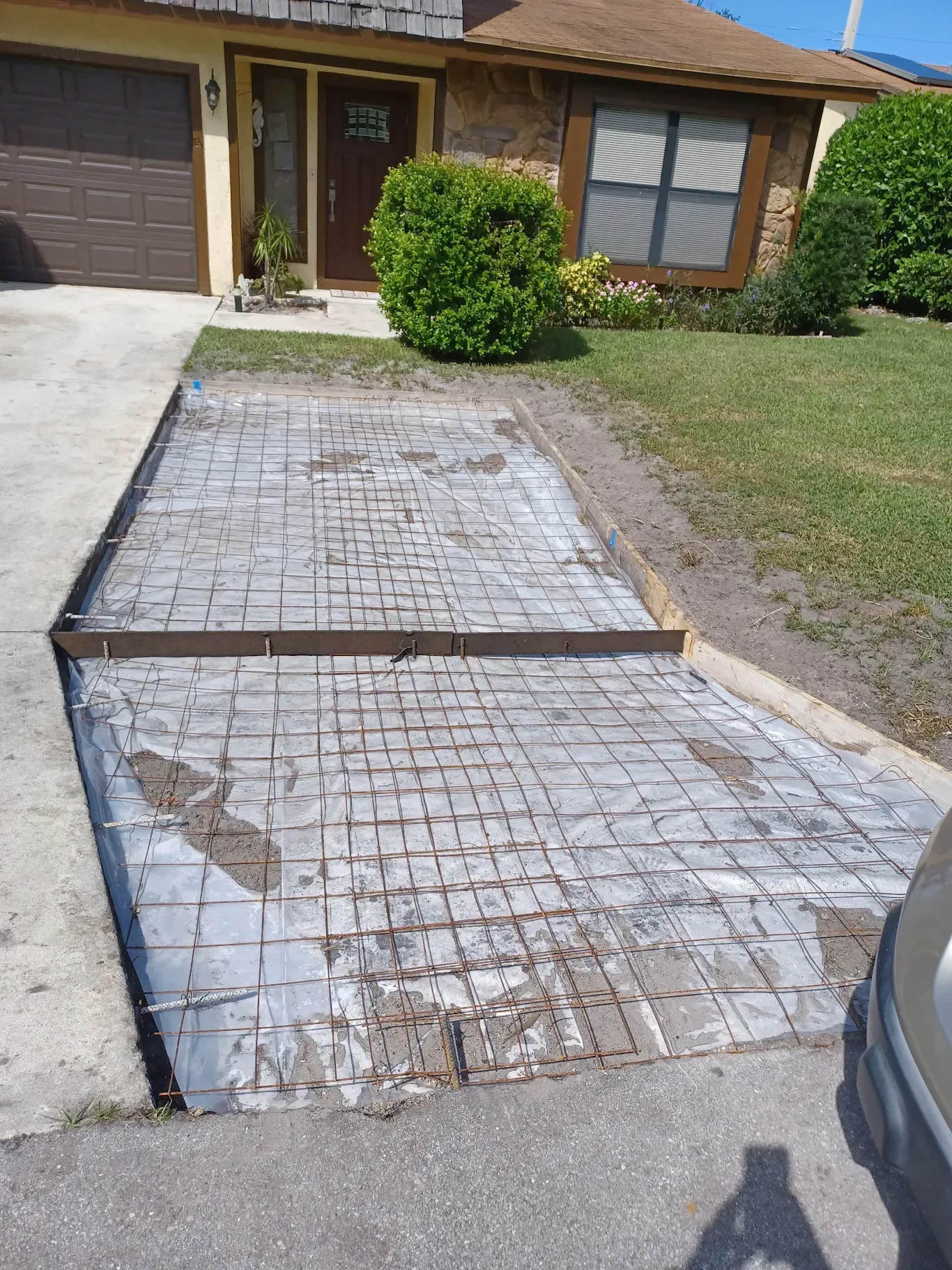 Damaged cracked driveway leading to a house with a garage and front lawn