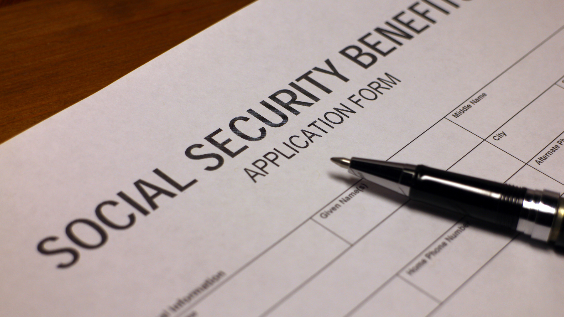 A pen rests on top of a social security benefit application form