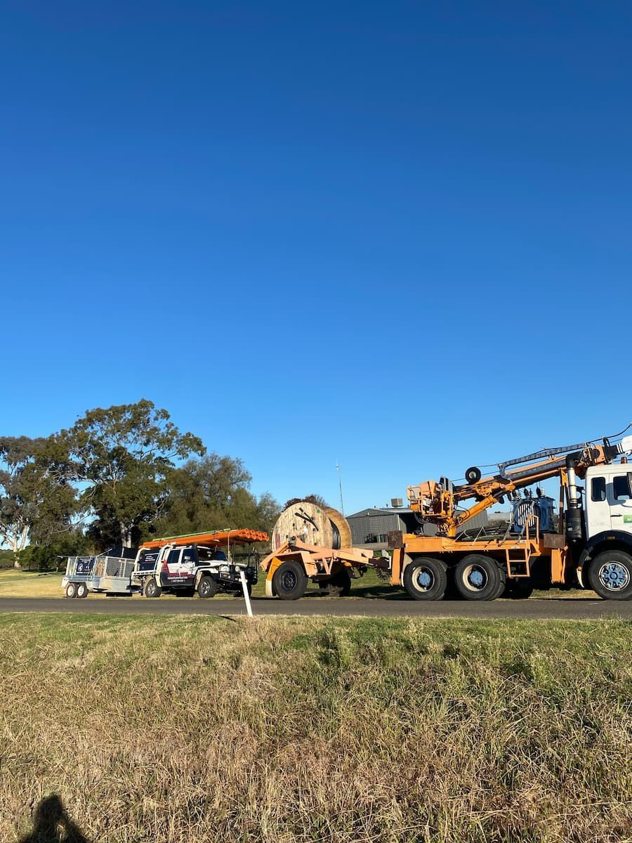 Vehicles Parked on Grass Under a Clear Blue Sky — Central West Power Construction in Orange, NSW