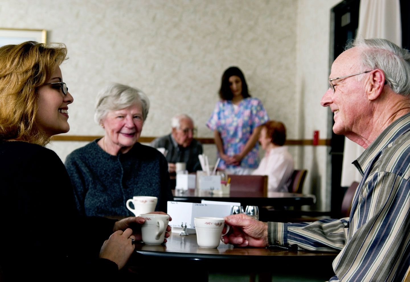 A man and a woman are sitting at a table drinking coffee