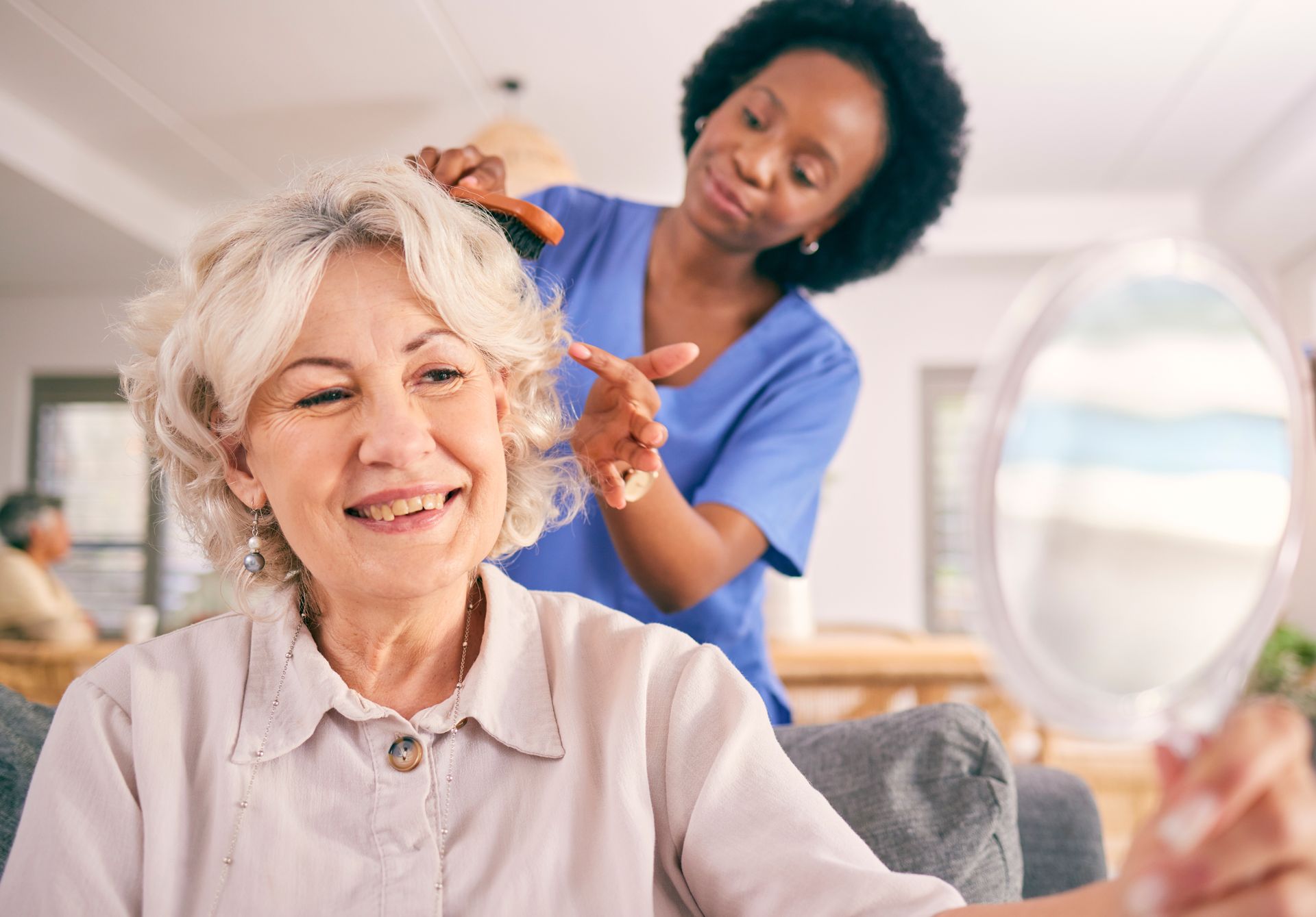 A caregiver helping an elderly woman style her hair