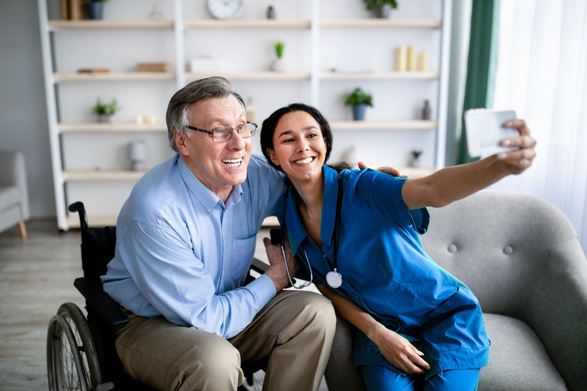 A nurse is taking a selfie with an elderly man in a wheelchair
