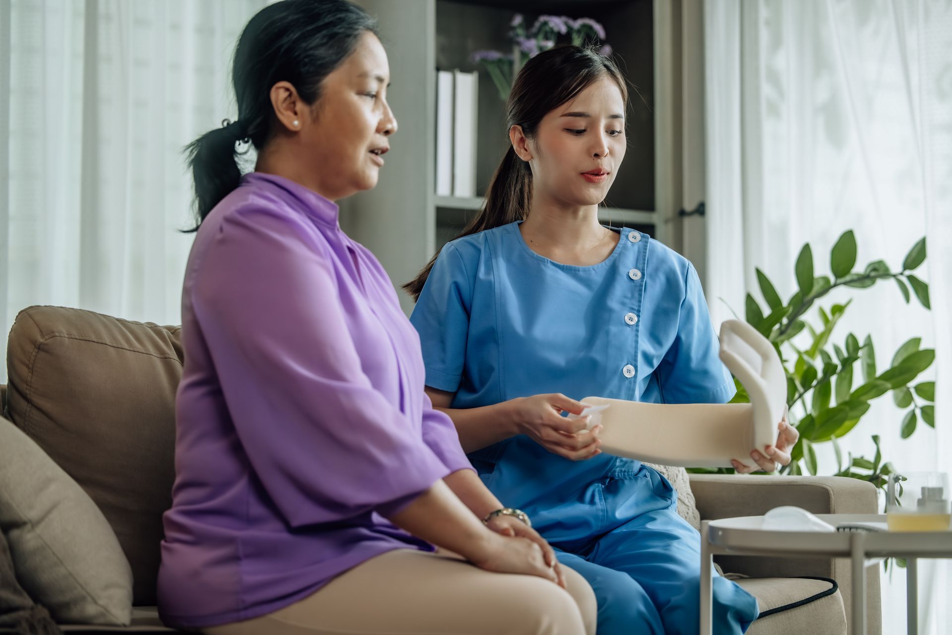 A nurse is giving an elderly woman a bandage on her leg