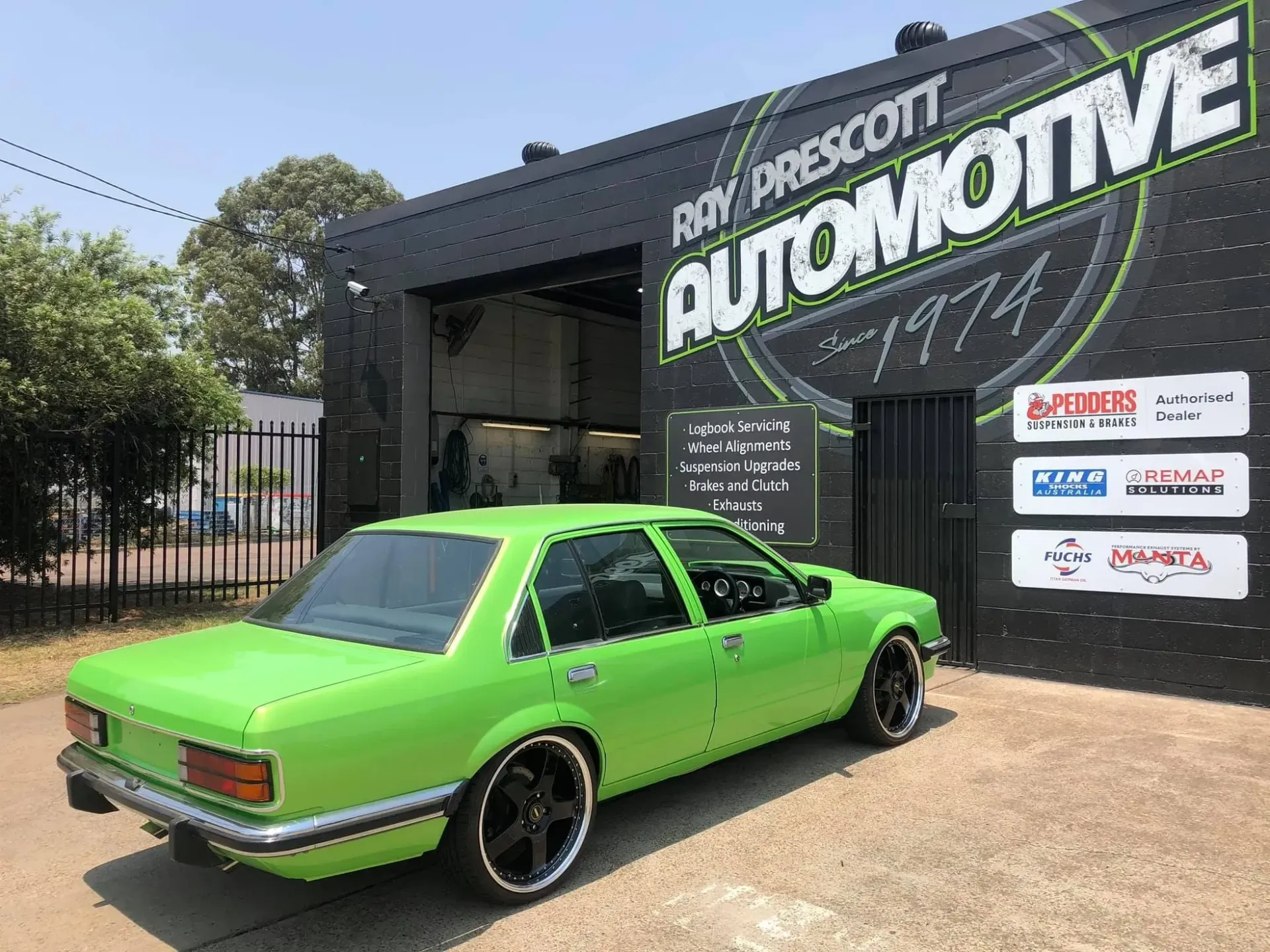 A green car is parked in front of an automotive shop — Mechanic in Cessnock