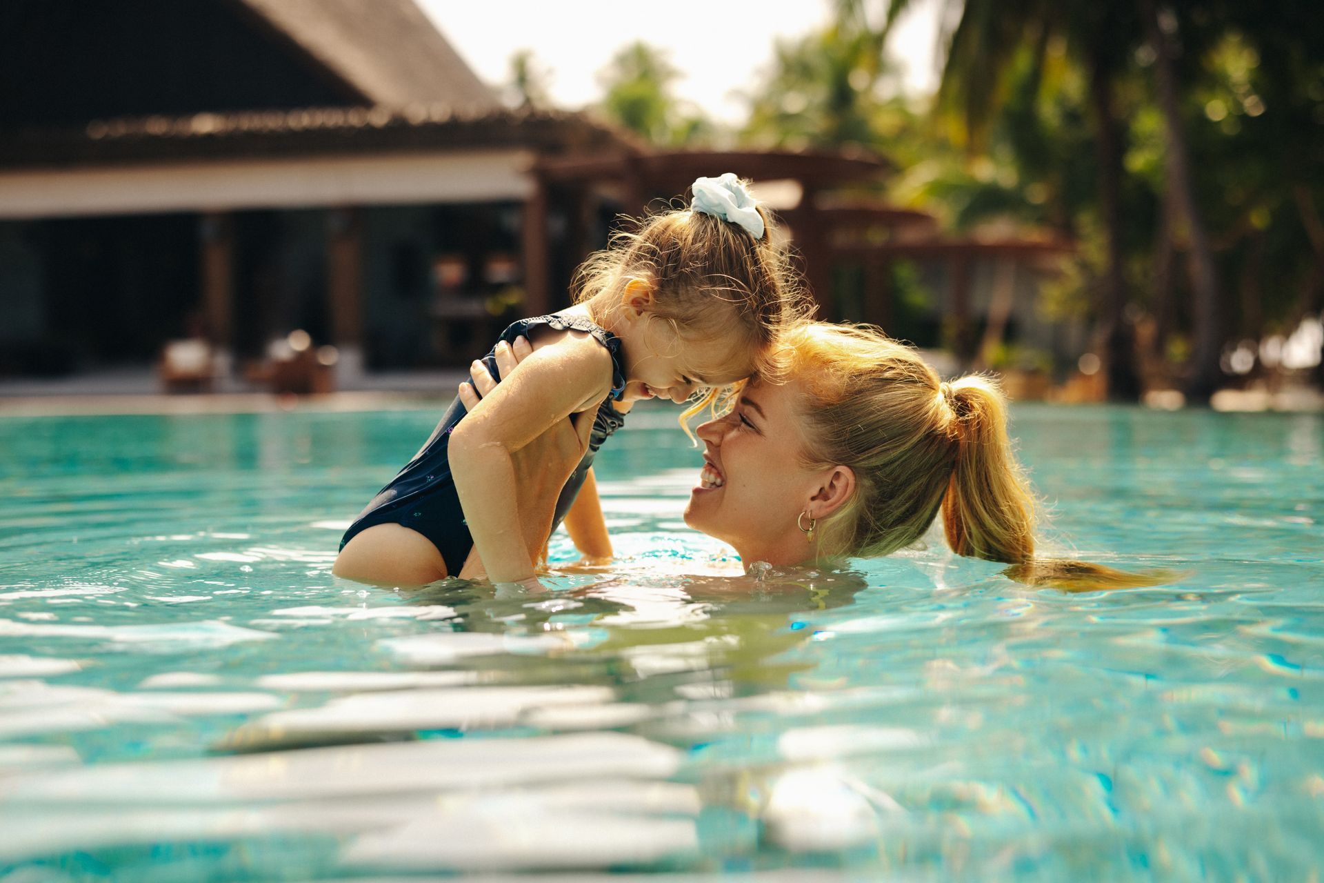 Mother and daughter sharing a loving moment at a pool.