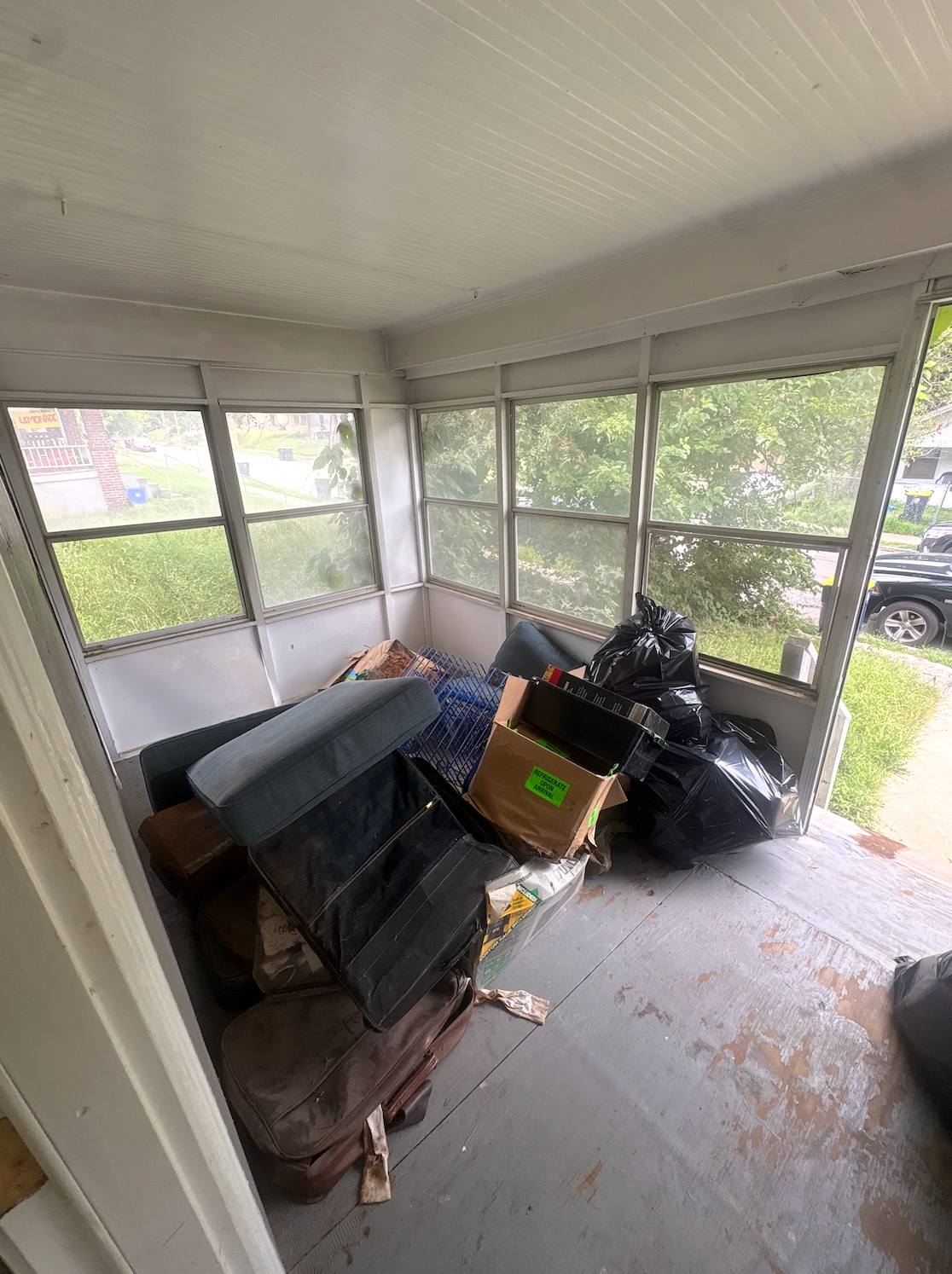 A collection of discarded items, including a blue mattress, an ironing board, and furniture, piled in an outdoor area.