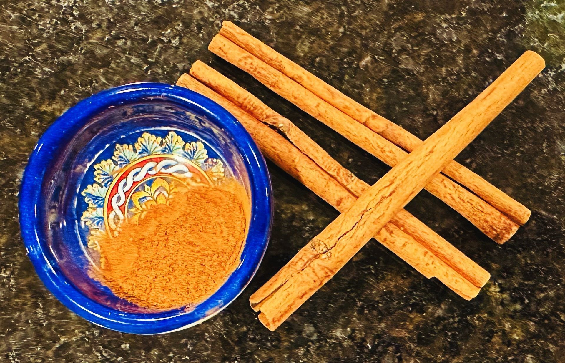 Cinnamon sticks next to a bowl of cinnamon powder