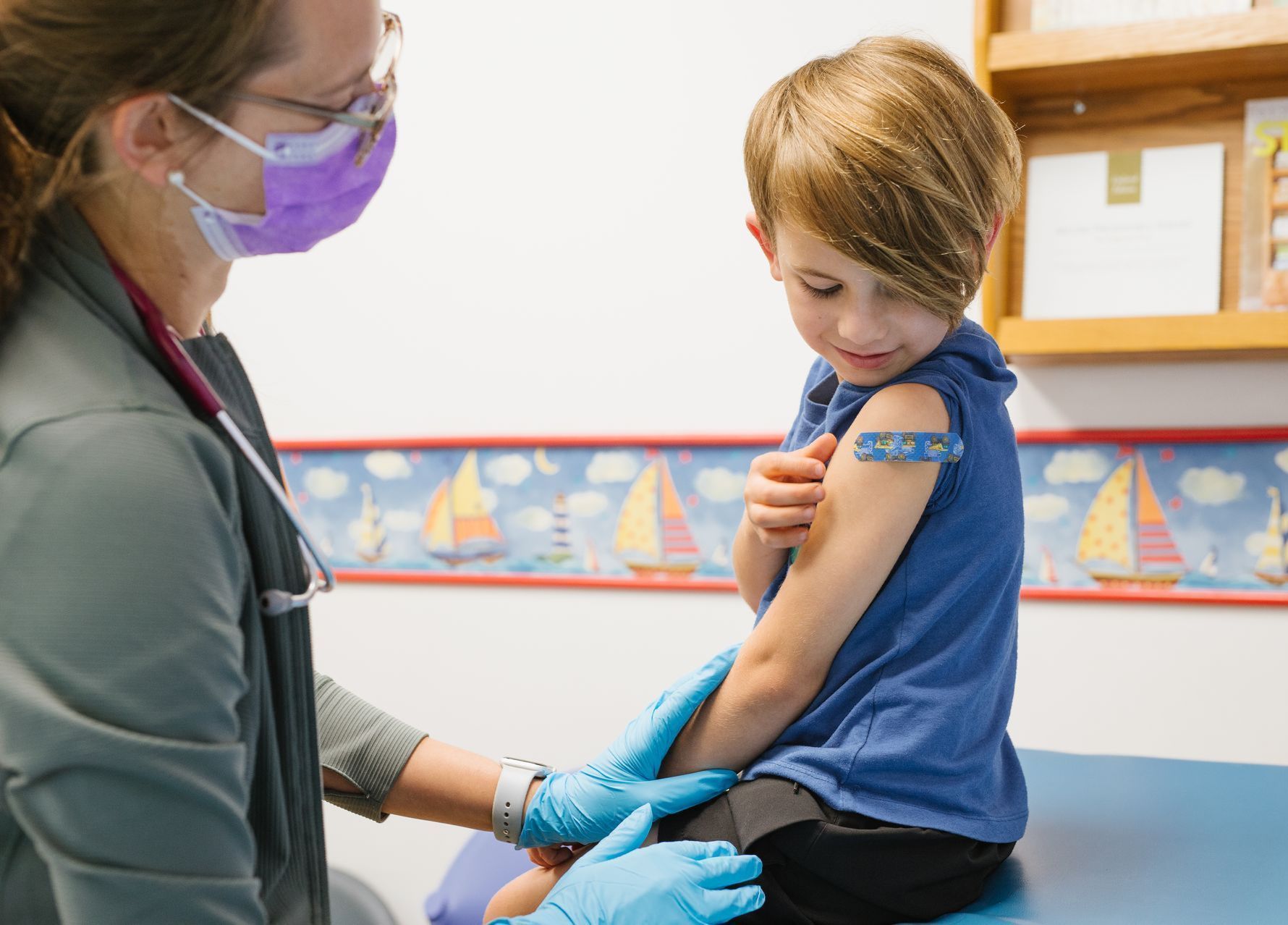A young boy is getting a vaccine from a doctor.
