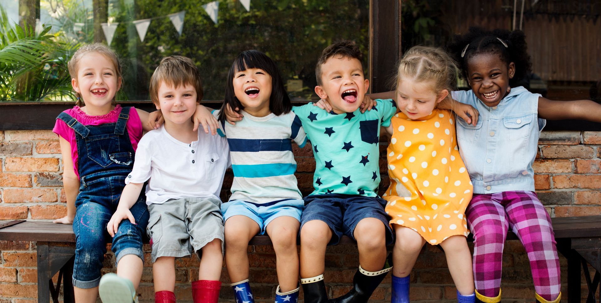A group of children are sitting on a bench together.