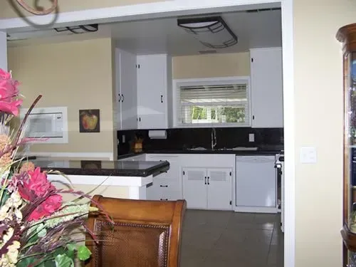 A kitchen with white cabinets and black counter tops