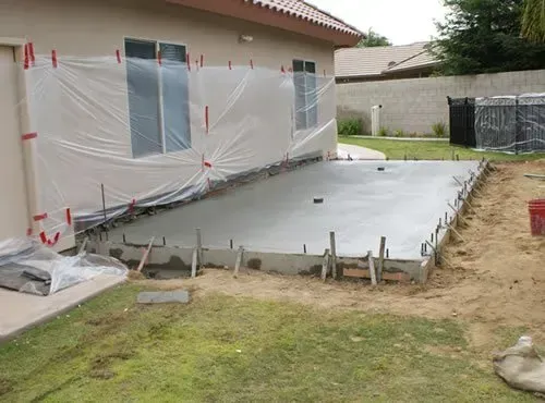 A concrete patio is being built in front of a house.