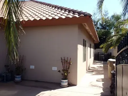 A house with a tiled roof and a potted plant in front of it