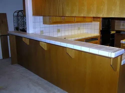 A kitchen with wooden cabinets and a tiled counter top.