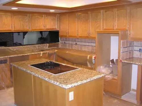 A kitchen with wooden cabinets and granite counter tops is being remodeled.