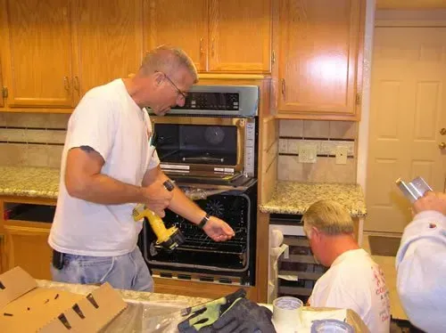 A man is working on an oven in a kitchen