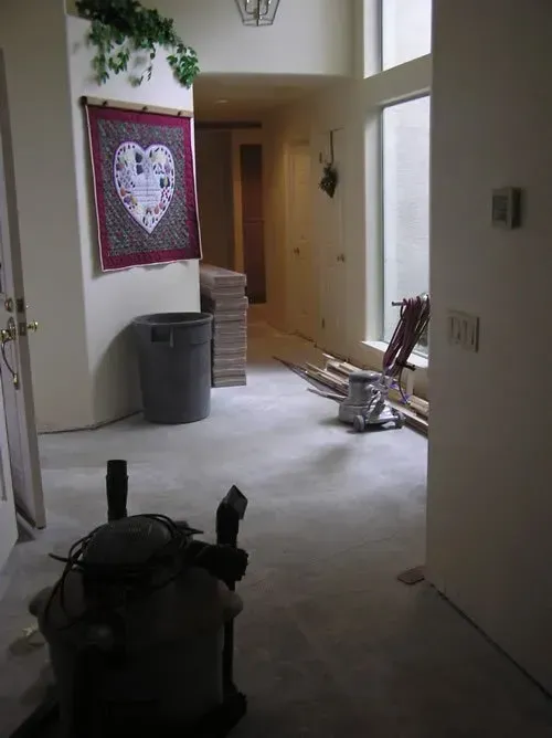 A room with a vacuum cleaner and a heart shaped quilt on the wall