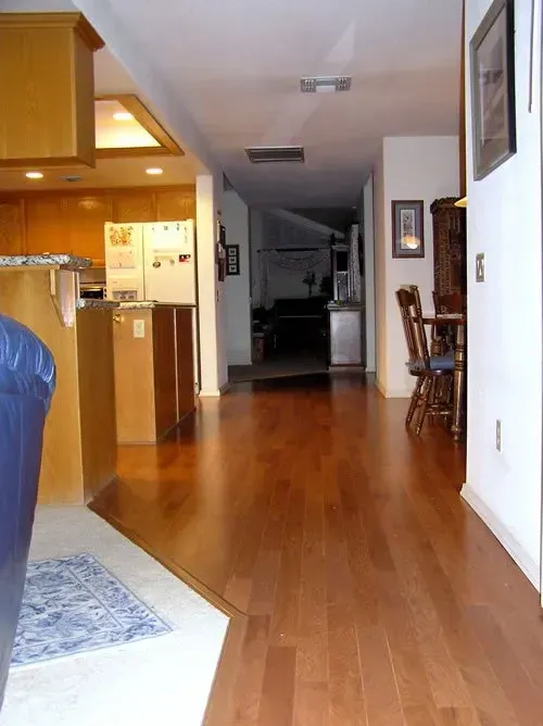 A hallway with hardwood floors leading to a kitchen