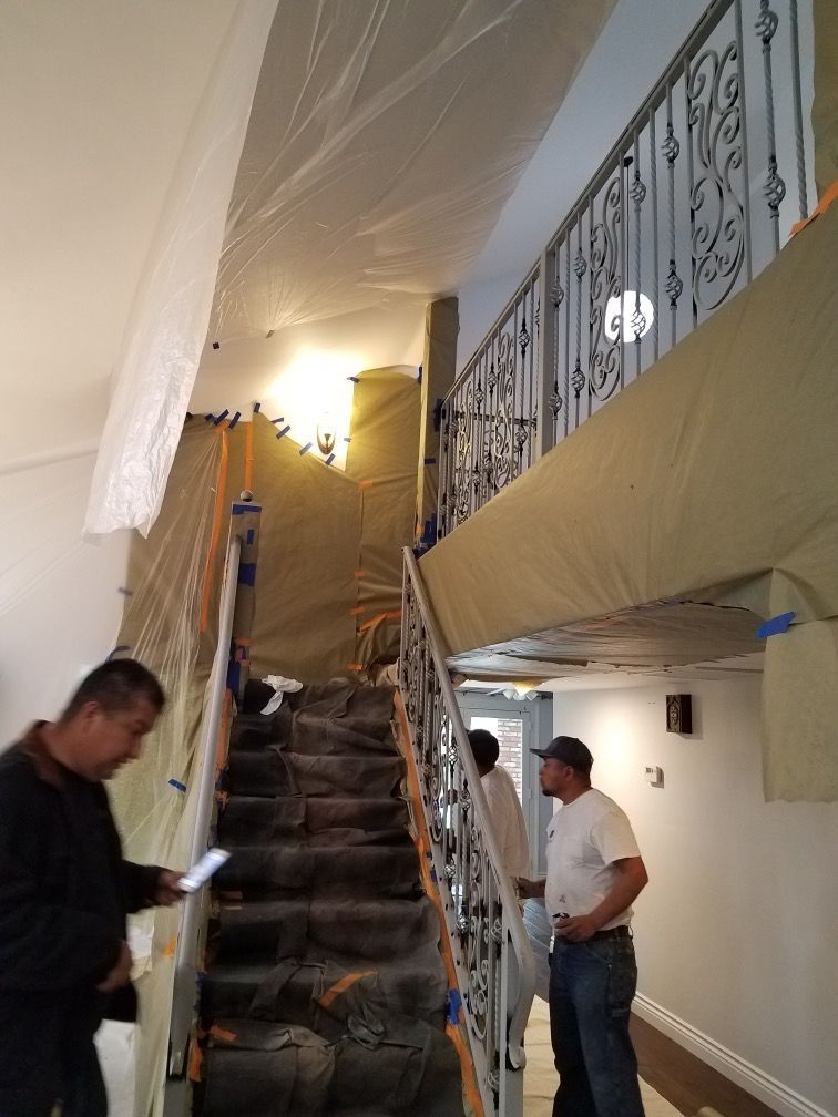 A man is standing next to a staircase that is covered in tarps.