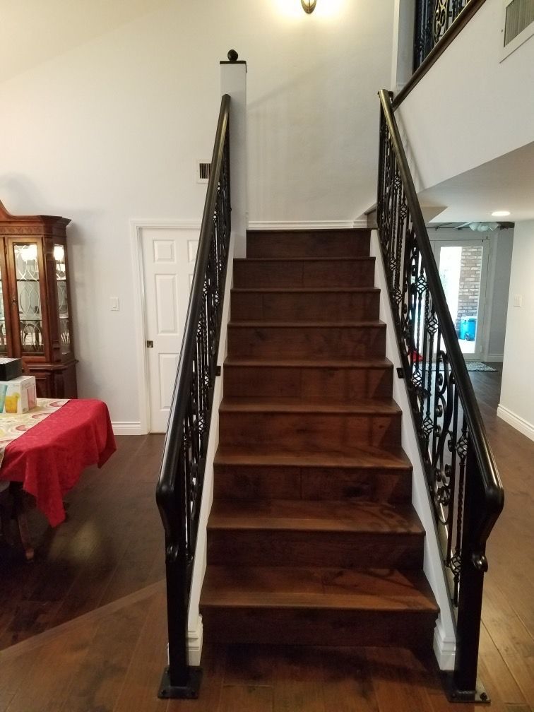 A wooden staircase with a wrought iron railing in a living room.