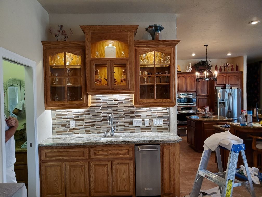 A kitchen with wooden cabinets and a ladder in the middle of the room.
