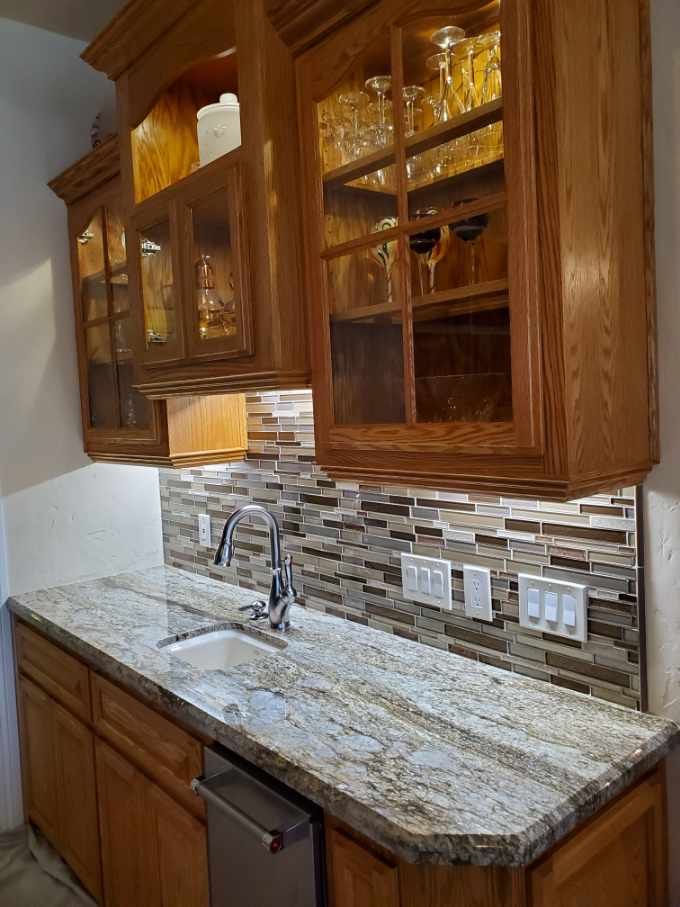 A kitchen with granite counter tops , wooden cabinets , a sink and a dishwasher.
