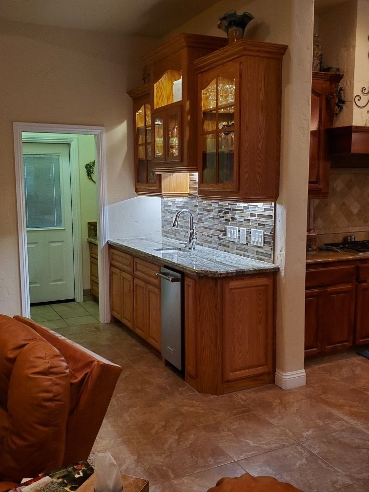 A kitchen with wooden cabinets , granite counter tops , and a stainless steel dishwasher.