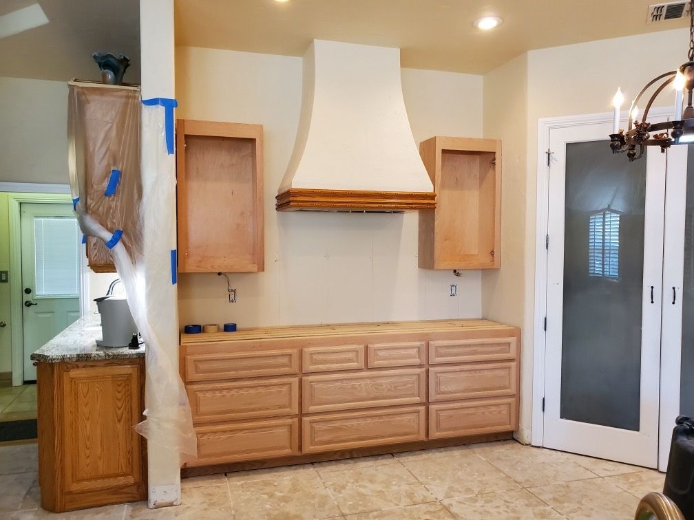 A kitchen with wooden cabinets and a hood is being remodeled.