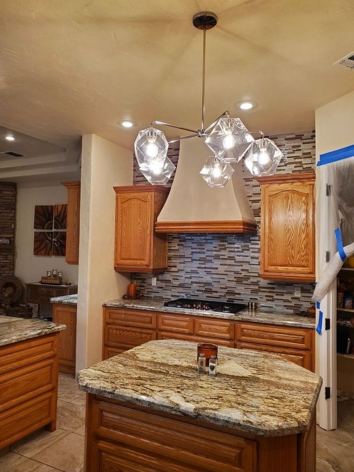 A kitchen with wooden cabinets , granite counter tops , and a large island.
