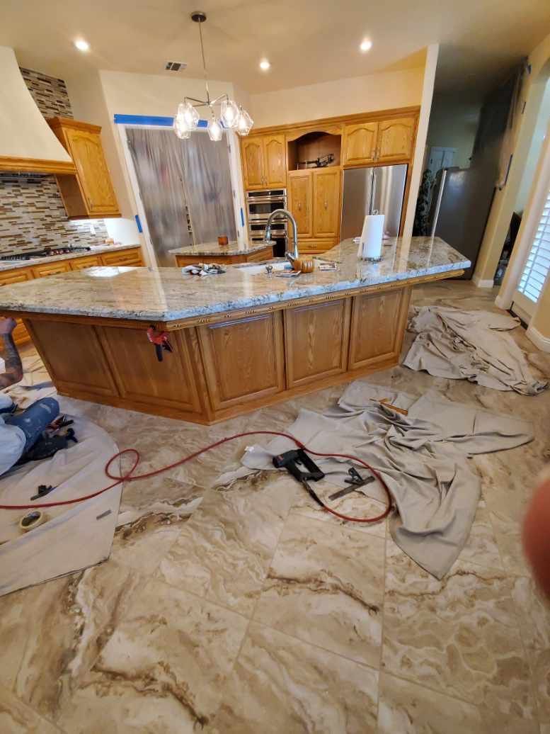 A man is kneeling on the floor in a kitchen.