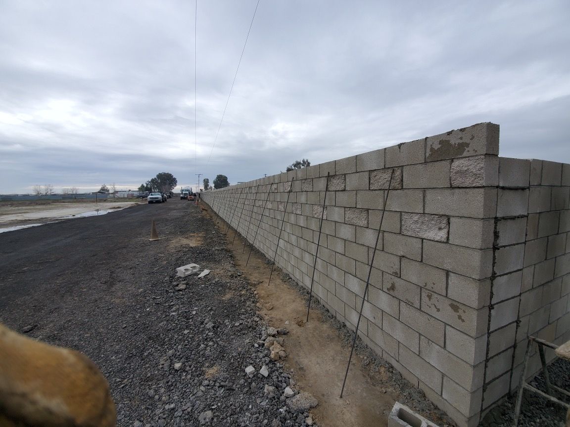 A brick wall is being built on the side of a road.