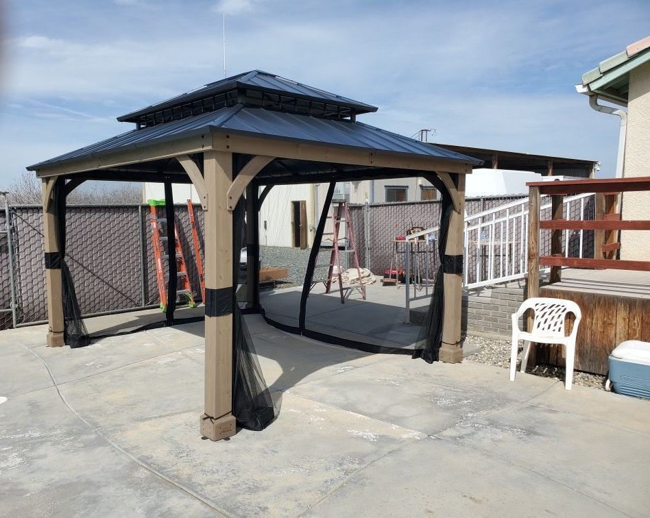 A gazebo with a screened in roof is sitting on a concrete patio.