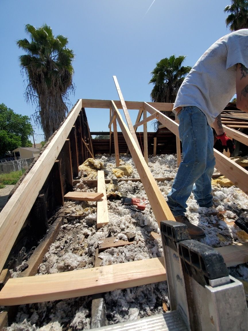 A man is working on a wooden structure with palm trees in the background