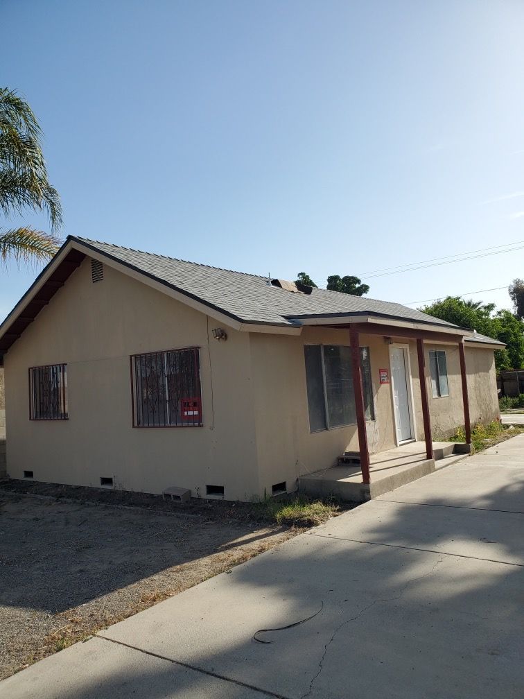 A small house with a gray roof is for sale
