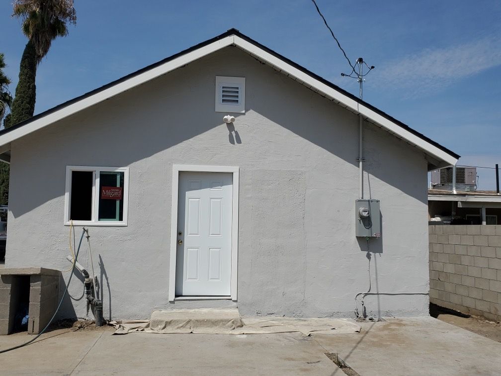 A gray house with a white door and a window
