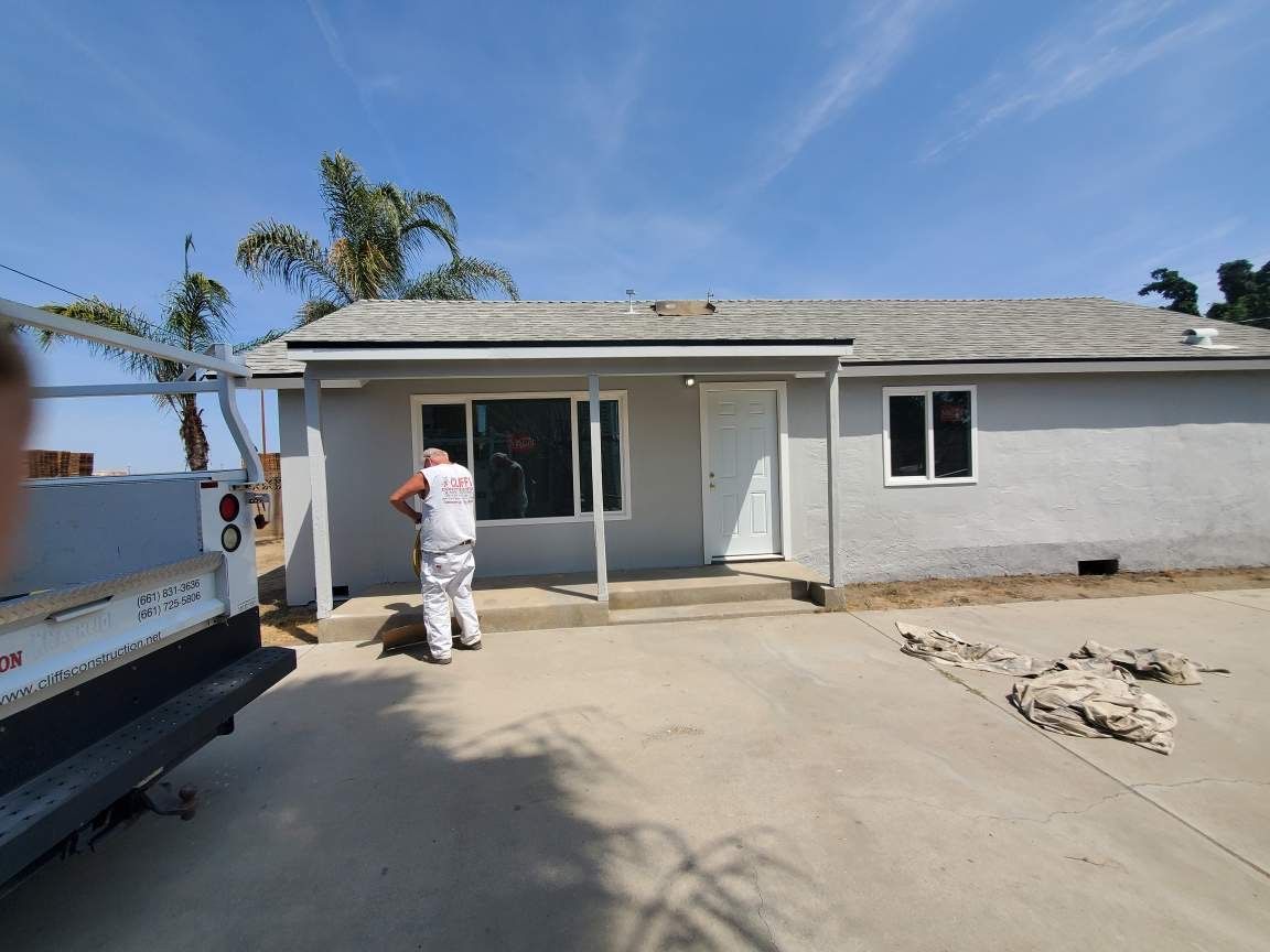 A man is standing in front of a house with a truck parked in front of it.