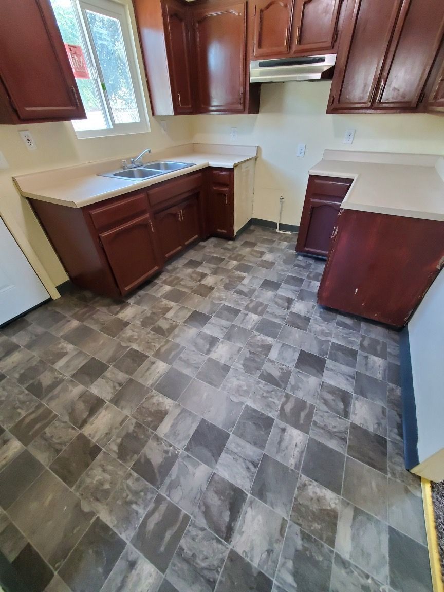 A kitchen with wooden cabinets and a tile floor.