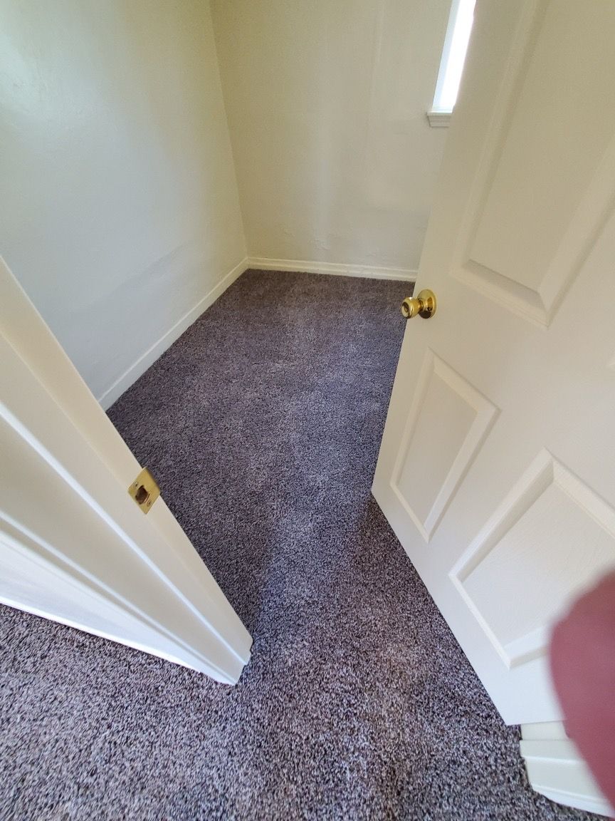 A room with a carpeted floor and a door that is open.