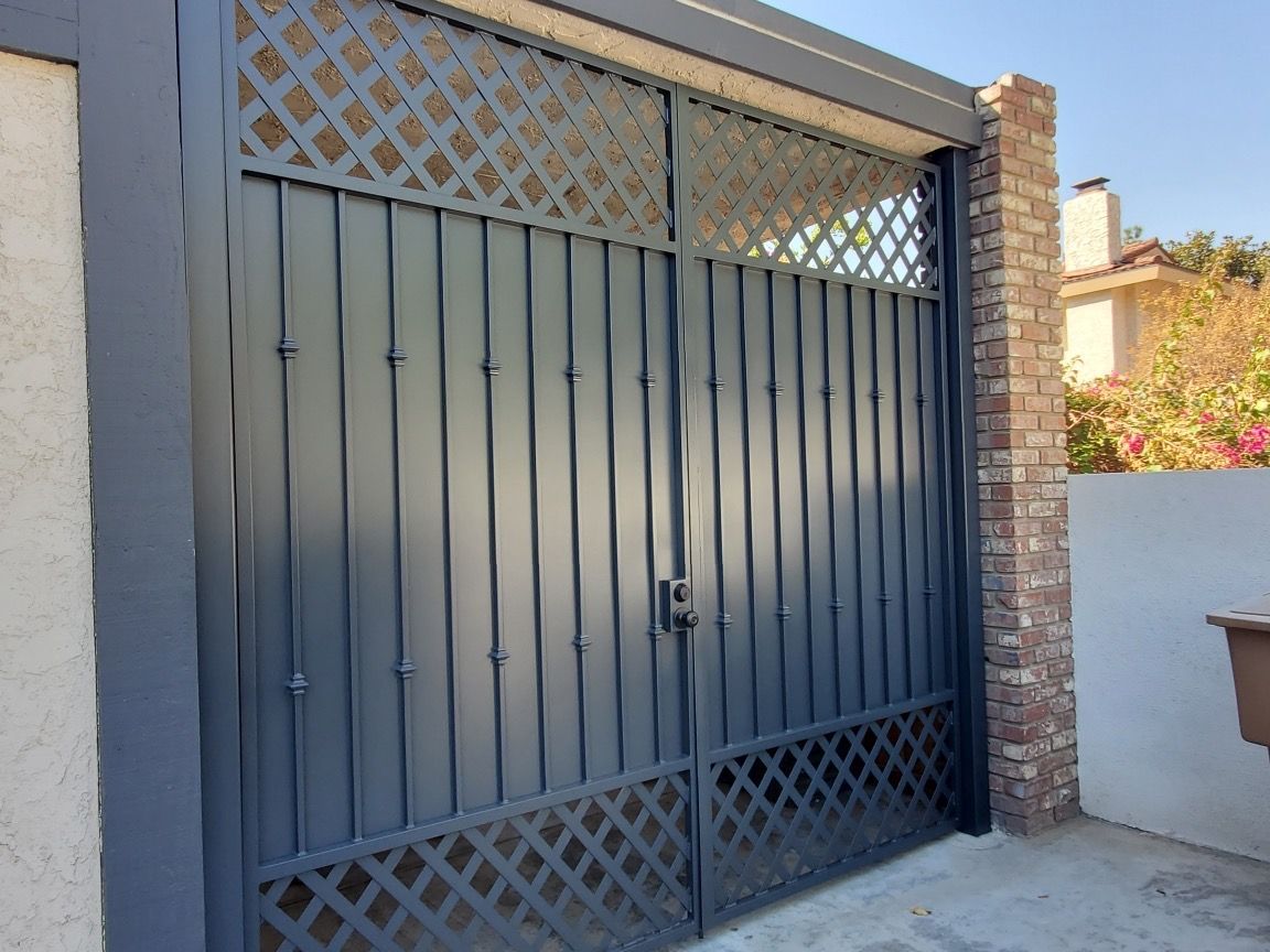 A black gate with a lattice design is sitting next to a brick wall.