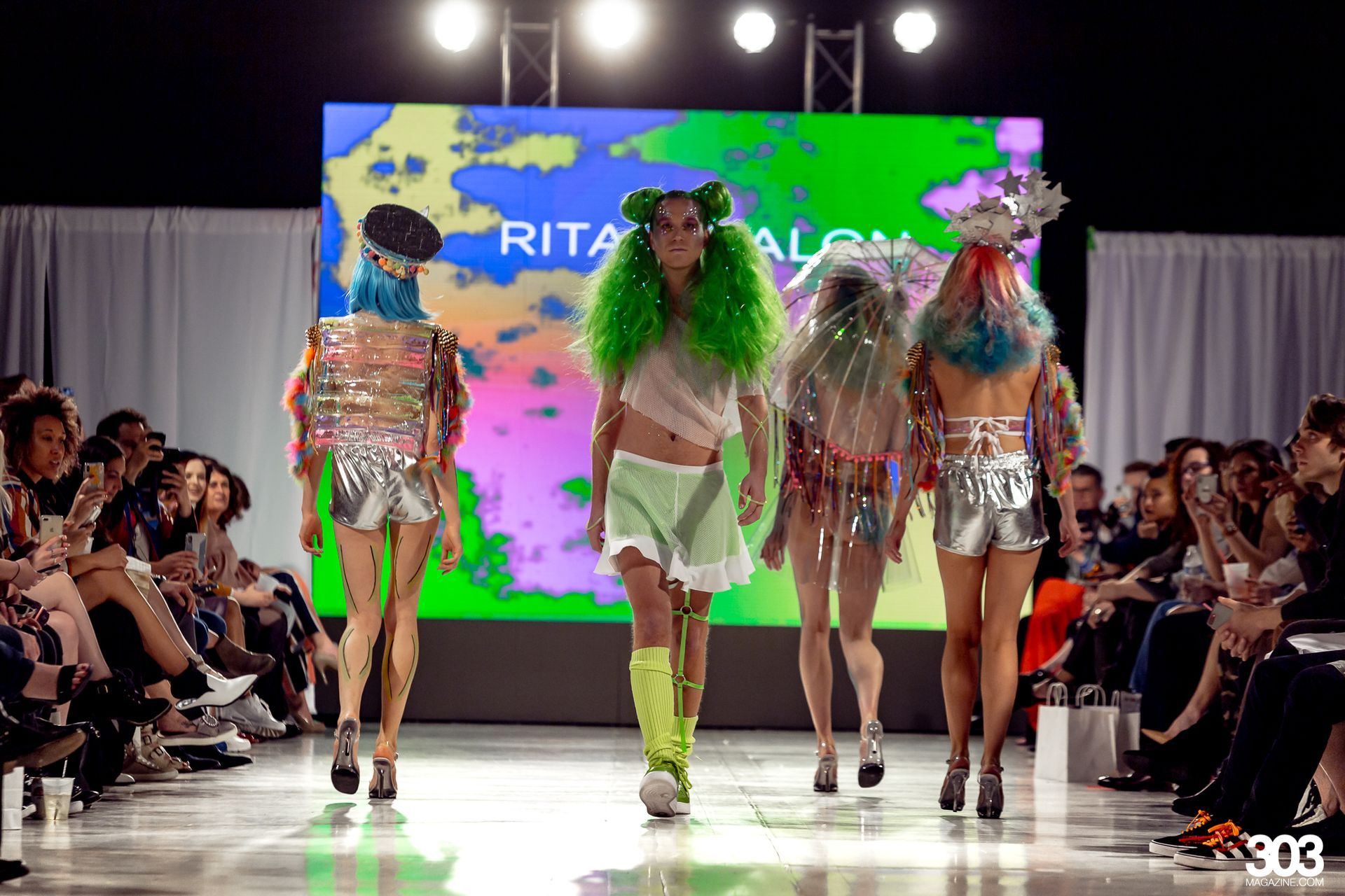 A group of women are walking down a runway at a fashion show.