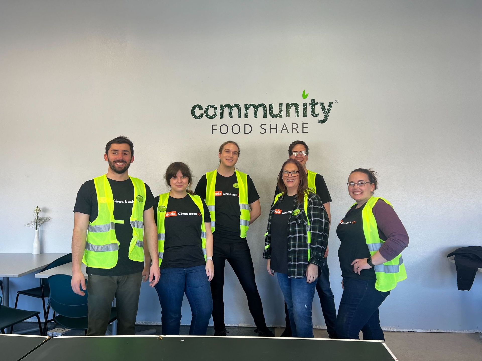 A group of people are posing for a picture in front of a wall that says community food share.