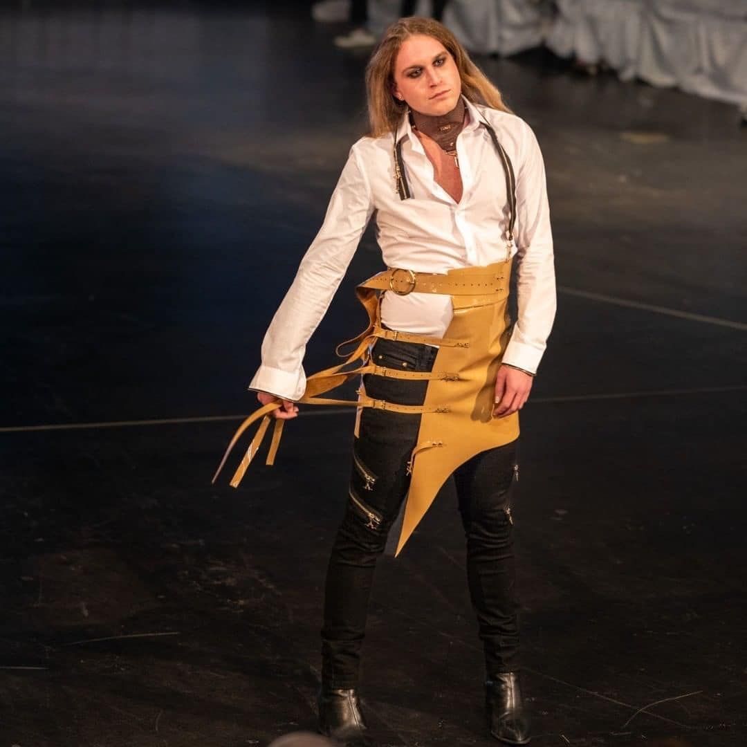 A woman in a white shirt and yellow skirt is standing on a stage
