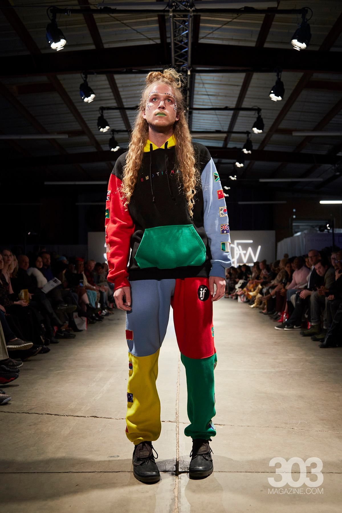 A model is walking down the runway at a fashion show wearing a colorful outfit.