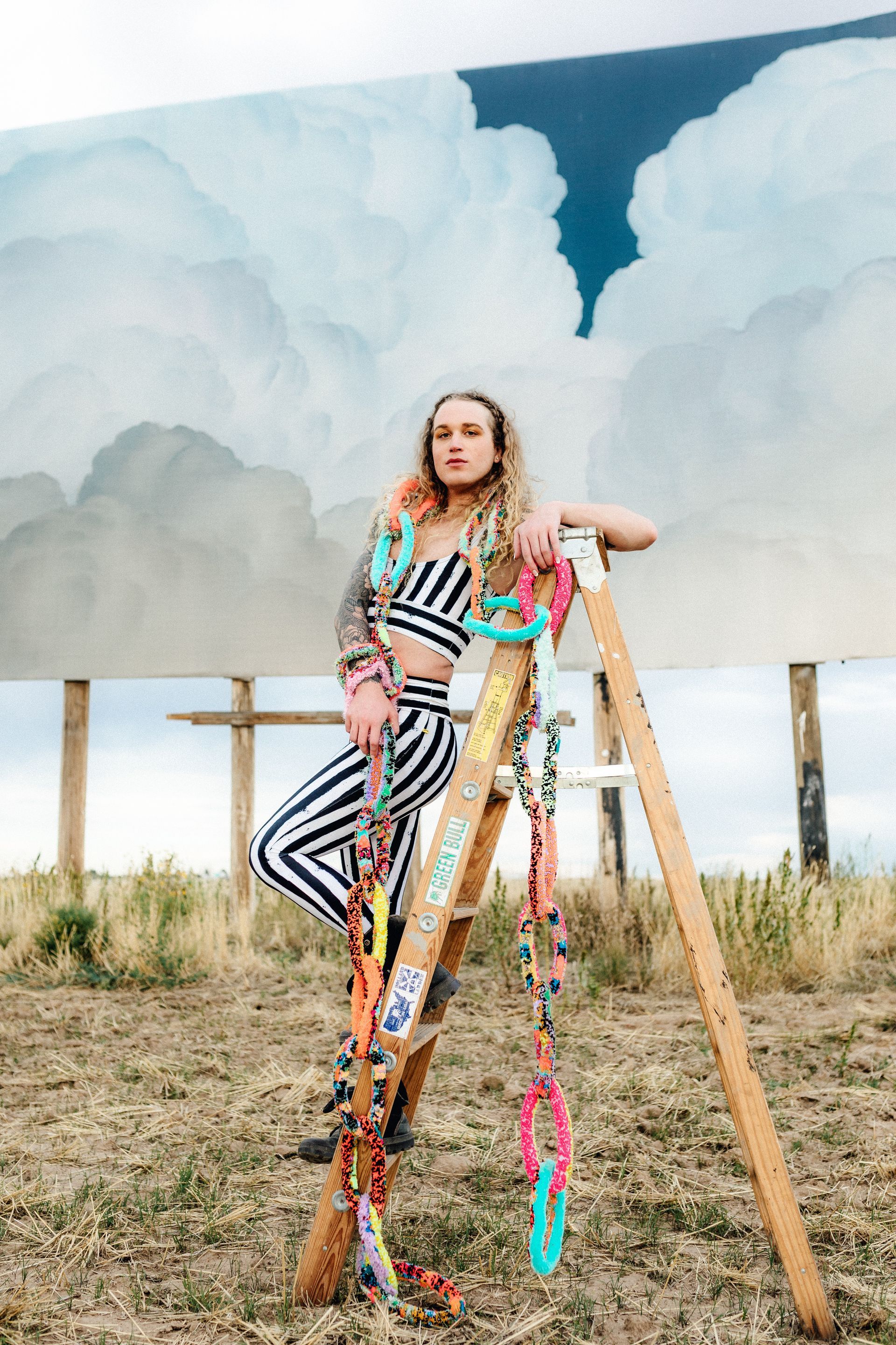 Scotty Strehlow is standing on a ladder in front of a billboard for a photo shoot.