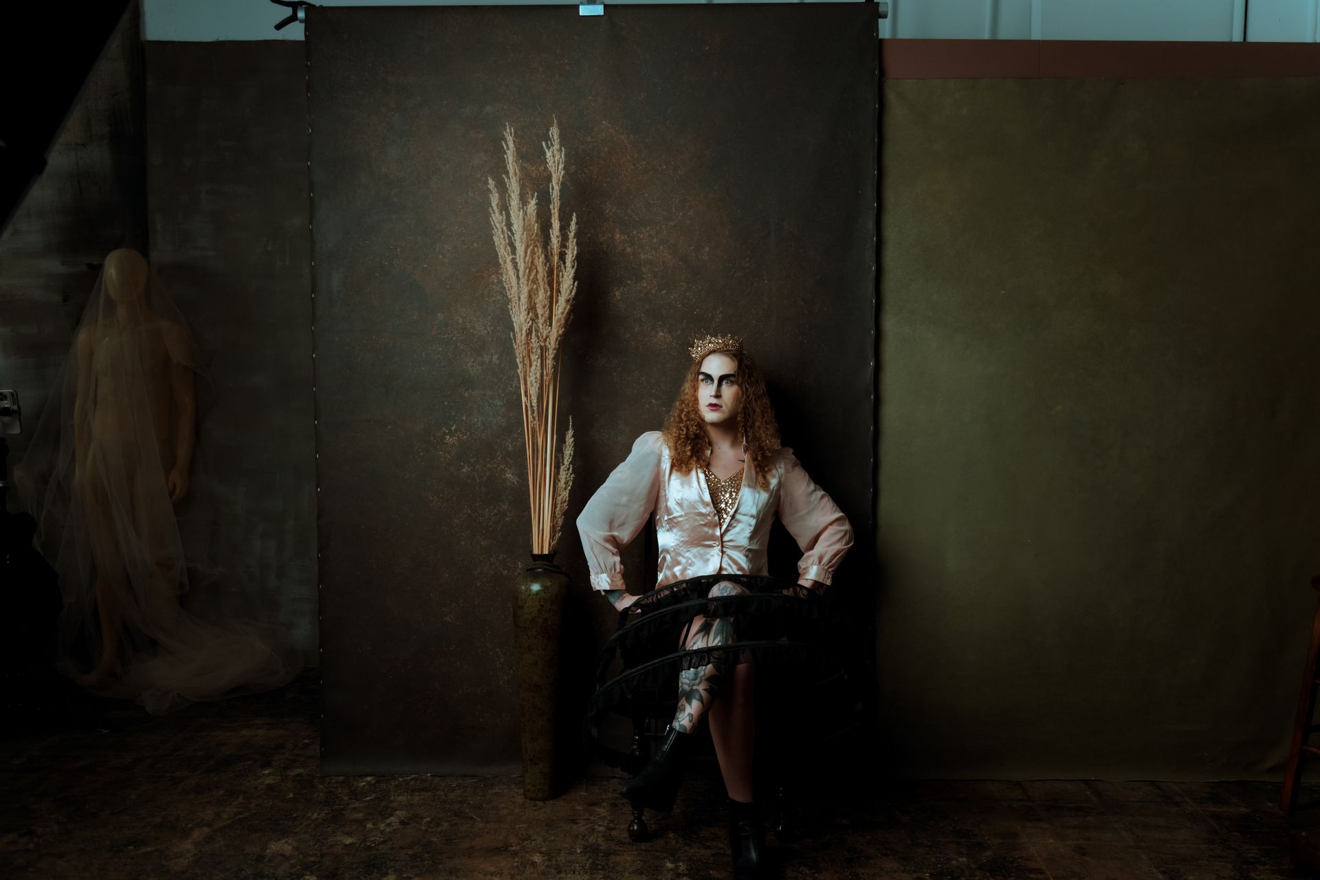 A woman is sitting in a chair in front of a wall for a fashion photo shoot.