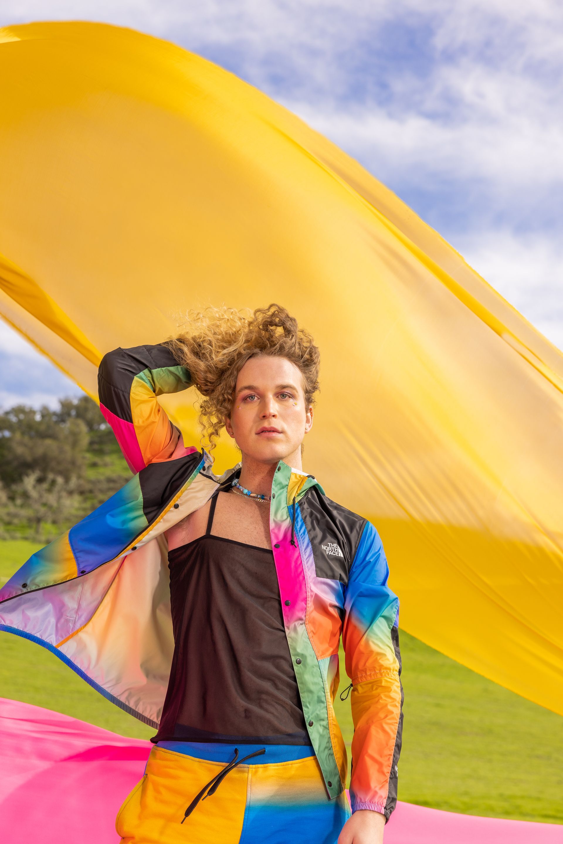 Scotty Strehlow, in a colorful jacket by The North Face, is standing in front of a large yellow flag.
