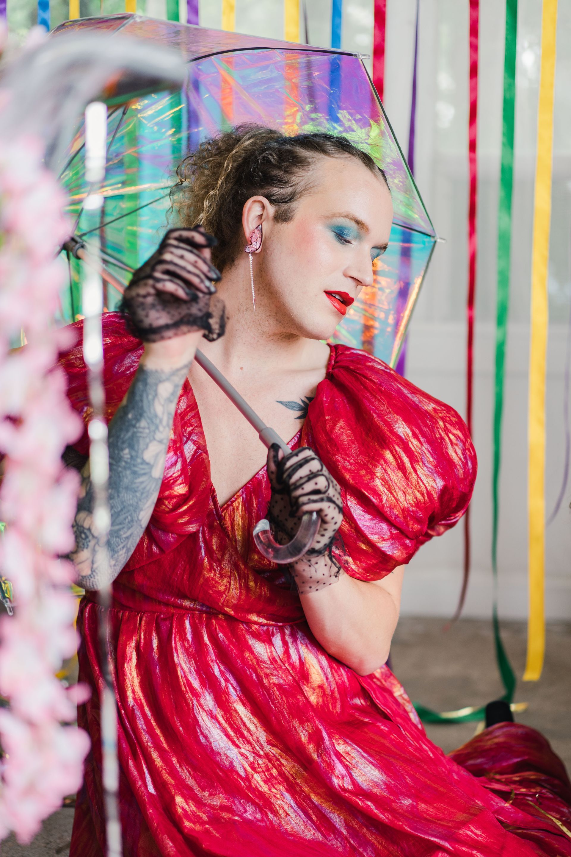 A woman in a red dress is holding an umbrella for a photo shoot.