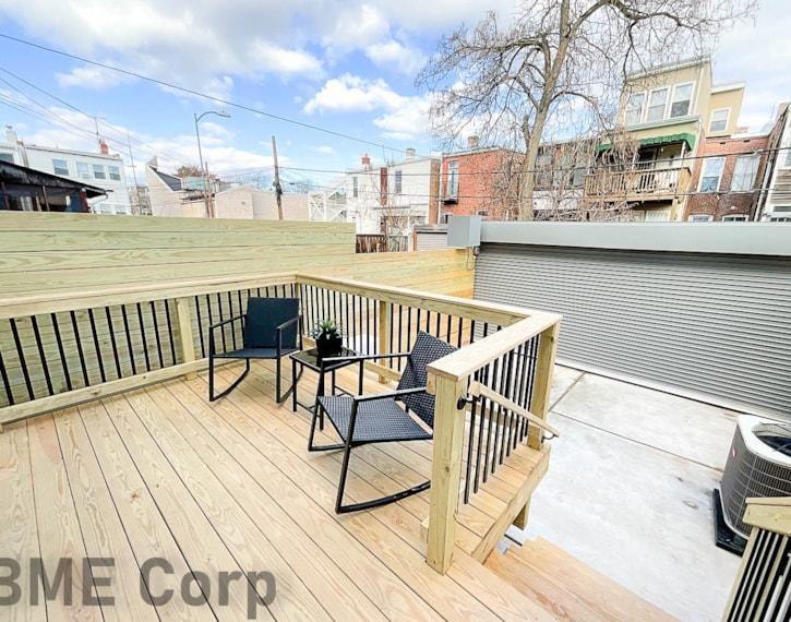 Backyard wooden deck with patio table and chairs beside a gray garage
