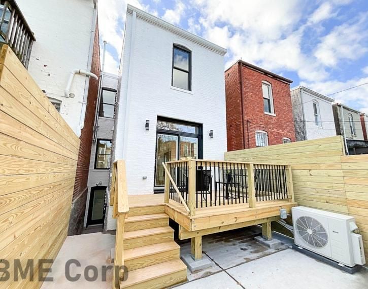 Small modern townhouse patio with wooden deck, steps, privacy fencing, and outdoor AC unit