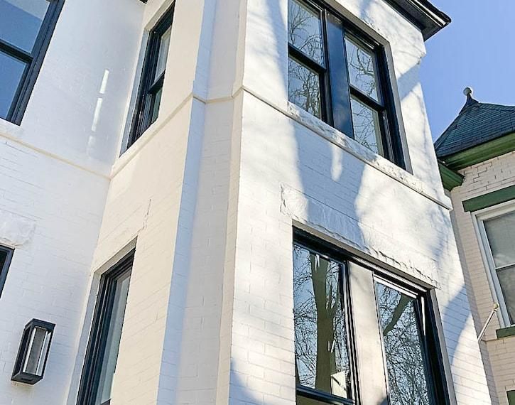 White stucco building with tall black-trimmed windows in sunlight