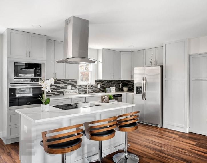 Modern kitchen with white cabinets, stainless steel appliances, and a large island with three stools.